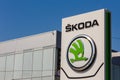 Green logo of car brand skoda on on promotional stand at sunny day in front of a dealership building.
