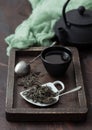 Green loose tea with vintage strainer infuser and iron teapot with cup in wooden box with green cloth