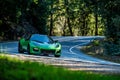 Green Lotus sports car driving through some turns in the woods