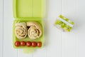 Green lunchbox with scrolls and tomato Royalty Free Stock Photo
