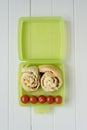 Green lunchbox with scrolls and tomato Royalty Free Stock Photo