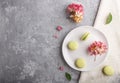 Green macarons or macaroons cakes on white ceramic plate on a gray concrete background top view