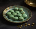 Green macaroons on a turquoise plate on a dark background