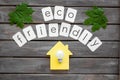 Green maple leaves, house figure, bulb and eco friendly text for ecology concept on wooden background top view Royalty Free Stock Photo