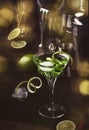 Green martini alcoholic cocktail in glass with dry gin, vermouth, liquor, lime zest and ice, steel bar tools, dark background Royalty Free Stock Photo