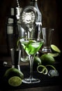 Green martini alcoholic cocktail in glass with dry gin, vermouth, liquor, lime zest and ice, steel bar tools, dark background Royalty Free Stock Photo