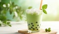 Green matcha bubble tea with ice cubes in cup on white wooden table over light green background softlight Royalty Free Stock Photo