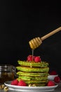 Green matcha homemade pancakes with fresh raspberries, pistachio and flowing honey. healthy breakfast dessert Royalty Free Stock Photo