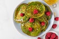 Green matcha homemade pancakes with fresh raspberries, pistachio and honey on white background. top view Royalty Free Stock Photo