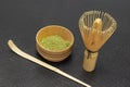 Green Matcha tea powder in a wooden bowl. Bamboo whisk and spoon on the table Royalty Free Stock Photo
