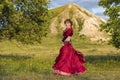 On green meadow against of mountain and summer sunset, young girl in ball gown is dancing incendiary dance. Royalty Free Stock Photo
