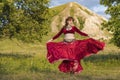 On green meadow against of mountain and summer sunset, young girl in ball gown is dancing incendiary dance. Royalty Free Stock Photo