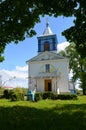 White and blue church under the green crowns of trees. Royalty Free Stock Photo