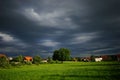 Green meadow in front of a village with beautiful houses with a dramatic sky in the background