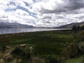 Green meadow near lagoon and distant mountains