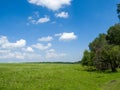 Green meadows and fields. White clouds in the blue sky