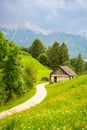 Green meadows with rural road, wooden house, mountains and forest on backgound at sunset in summer, Italy Royalty Free Stock Photo