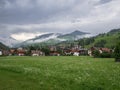 Green Meadows, Wooden Houses in the Village of San Vigilio di Marebbe and Italian Alps Mountains in the Background on a Cloudy Royalty Free Stock Photo