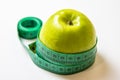 Green measuring tape over green apple. Diet and Healthy life, loss weight concept. Isolated. White background Royalty Free Stock Photo