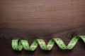 Green measuring tape over brown wooden background