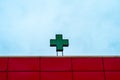 Green medical cross on the building against the blue sky. Neon green sign cross Royalty Free Stock Photo