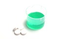 Green medical liquid in a plastic cup with pills Royalty Free Stock Photo
