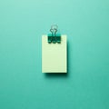 Green memo paper, sticky notes with green binder clip on mint green background