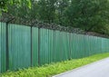 Green metal fence with barbed wire Royalty Free Stock Photo