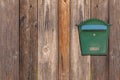 Green metal mail box hanging on right side of wooden house wall Royalty Free Stock Photo