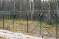 A green metal mesh fence with coiled barbed wire around the restricted area of a military facility Royalty Free Stock Photo