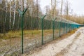 A green metal mesh fence with coiled barbed wire around the restricted area of a military facility Royalty Free Stock Photo