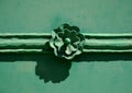 green metal plate door with rose shaped forged iron ornament and horizontal bar trim. architectural detail