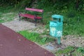 Metal trash can with wooden bench with wrought-iron legs