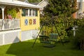 A green, metal vintage garden swing on the front yard of a traditional old style American home