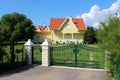 Green metal wrought fence with stone pillars in front of modern suburban family house with garage