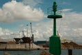 Green Metallic Lighthouse, Blue Sky with Clouds and Shipyard in Royalty Free Stock Photo