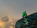 Green metro sign on the visor of entrance against evening sky background