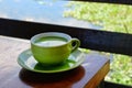 green milk tea in a green glass, placed on a table, with a lake in the background Royalty Free Stock Photo