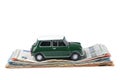 A green miniature car placed on top of a pile of euro bills isolated Royalty Free Stock Photo