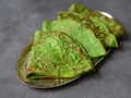 Green mint crepes on metal plate on gray background. Close up, selective focus. Gourmet breakfast. Maslenitsa. Russian thin crepes