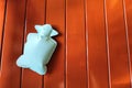 green or mint hot water bottle or bag on brown wooden background