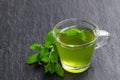 Green mint tea in clear glass cup on black stone background Royalty Free Stock Photo