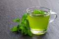 Green mint tea in clear glass cup on black stone background Royalty Free Stock Photo