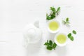 Green mint tea with fresh leaves in cups and teapot overhead on white wooden table, healthy warming drink, antioxidant beverage Royalty Free Stock Photo