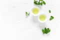 Green mint tea with fresh leaves in cups and teapot overhead on white wooden table, healthy warming drink, antioxidant beverage Royalty Free Stock Photo