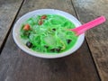 green mixed fruits ice dessert, consisting of watermelon pieces and black jelly pieces. in a white bowl a red spoon Royalty Free Stock Photo