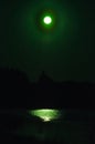 Green moon in the night sky reflected in a lake, Finland. Royalty Free Stock Photo