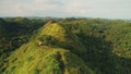 Green mount top aerial: travelers hiking path to building on hill top. Philippines nature landscape Royalty Free Stock Photo