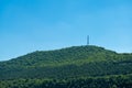 Green mountain next to sea with radio tower on top Royalty Free Stock Photo