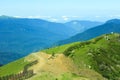 A green mountain range against the background of distant mountain peaks with a fence and a herd of cows in the foreground Royalty Free Stock Photo